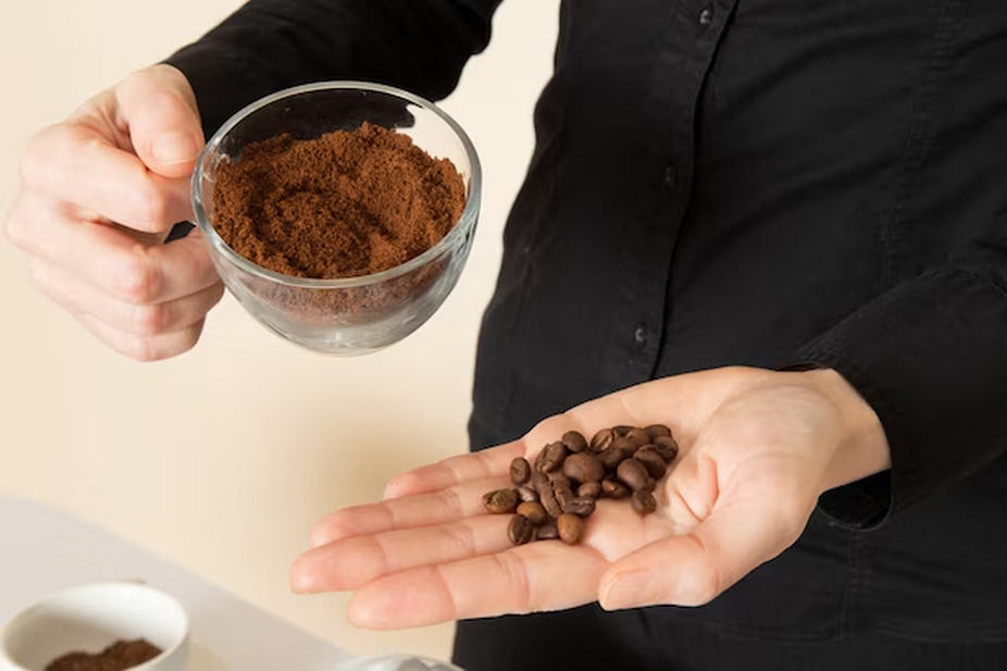 One hand holding coffee beans, the other hand with a cup filled with ground coffee