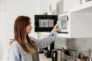 Woman placing glass in microwav