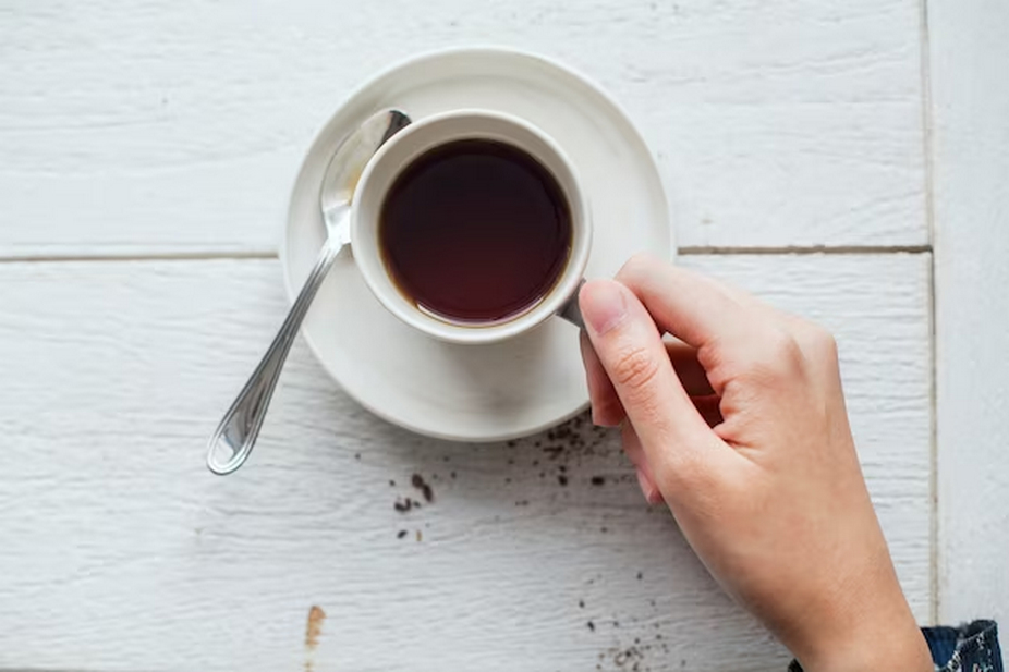 Hand with a cup of black coffee