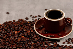 cup of coffee surrounded by coffee beans