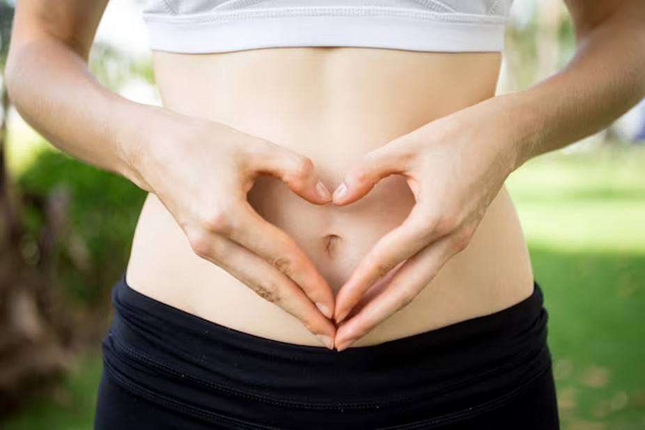 Woman forming a heart shape with her hand near her abdomen.